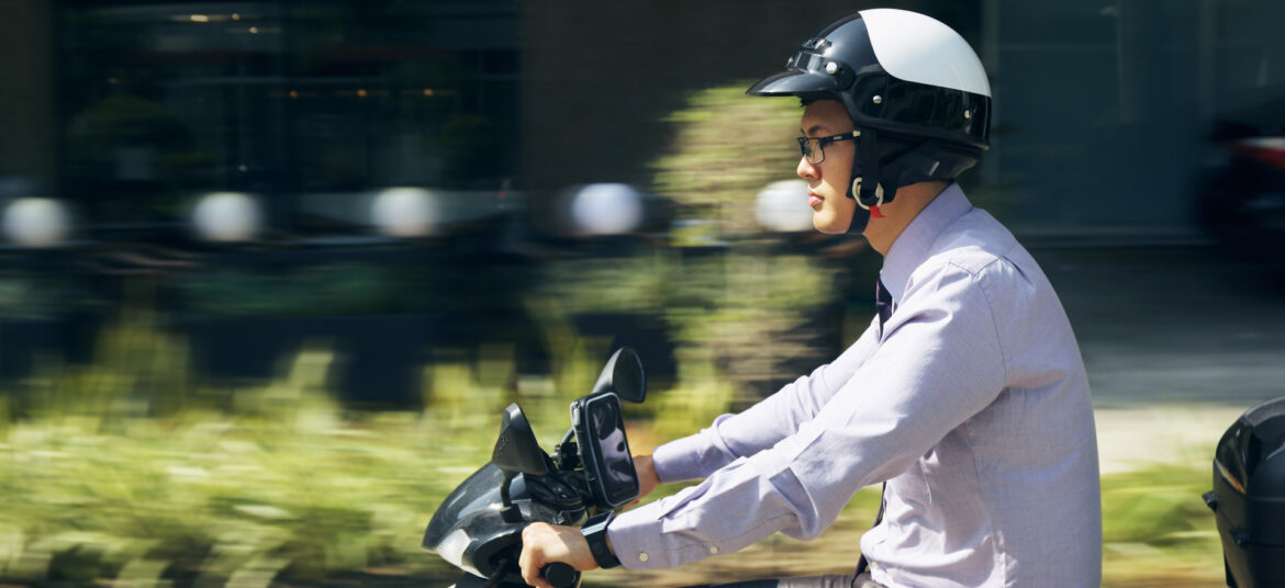 Young asian businessman commuting to job. The man rides a motorcycle with white helmet. Motion blurred background